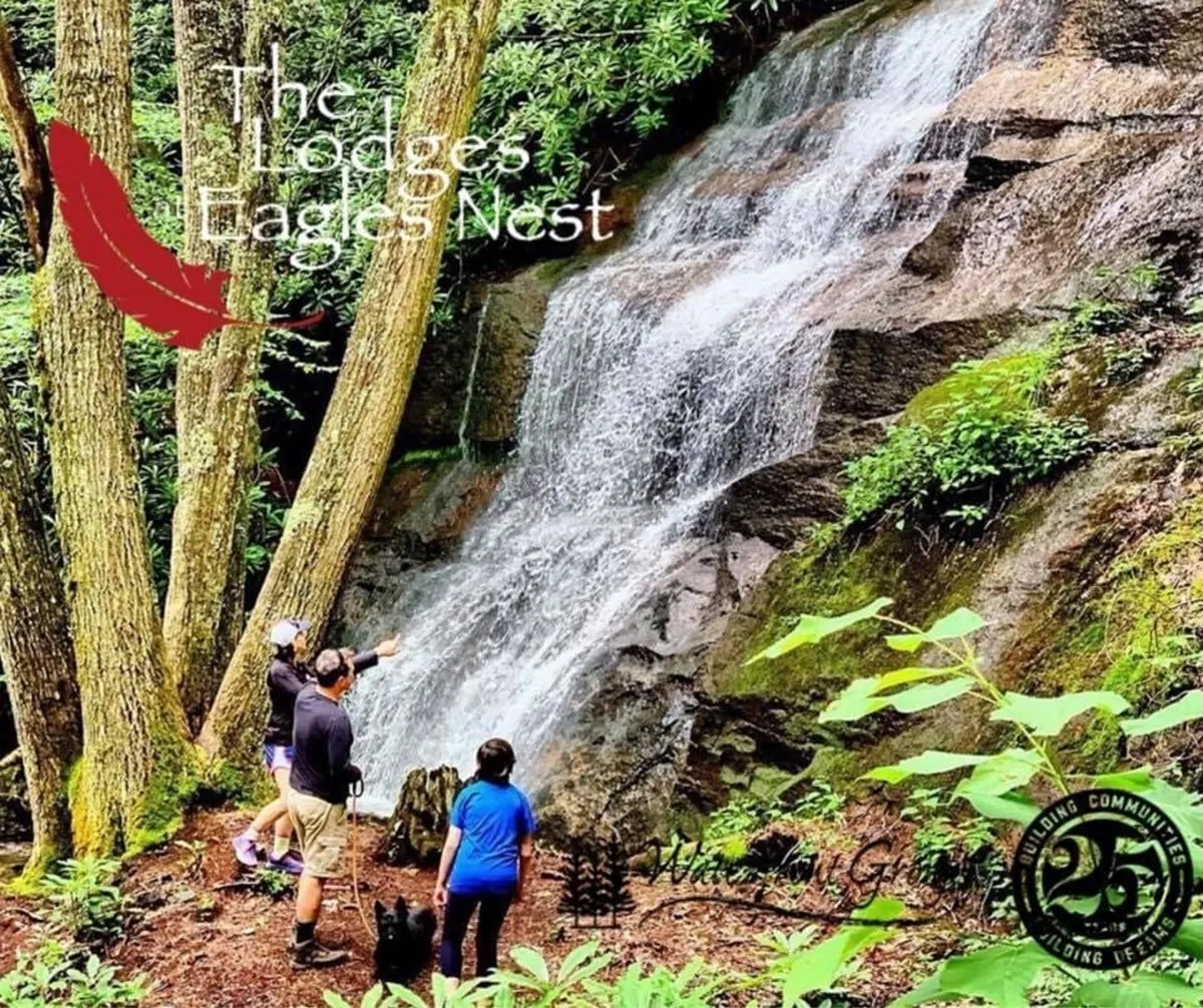 A lively moment at a local waterfall, with people and a dog enjoying hiking and exploring the natural area, surrounded by trees. The image evokes the joy of group adventures and discovering picturesque spots nearby.